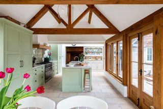 green kitchen in an oak frame extension with patio doors