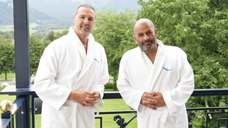 Paddy McGuinness and Chris Harris standing on a balcony dressed in white bathrobes in Paddy and Chris: Road Tripping