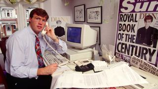 Andrew Morton at his desk pretending to take a call, around is are press cuttings about his tell-all book he collabed with Diana on
