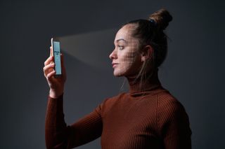 Woman holding a smartphone up to her face so the biometric scanner can read her face