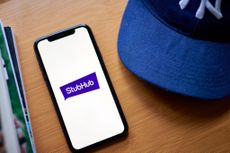 The StubHub logo on a smartphone on a table next to a New York Yankees baseball hat