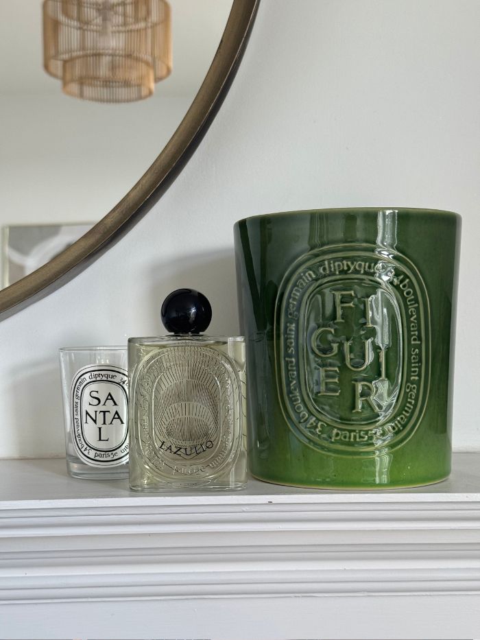 Diptyque Lazulio perfume on a mantelpiece, next to Diptyque candles