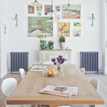 A large dining table with pendant lights and a gallery wall in the background