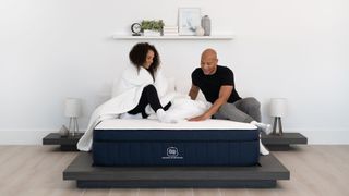 The best cooling mattress: Brooklyn Bedding Aurora Hybrid mattress with a couple sat on it, in a smart bedroom 
