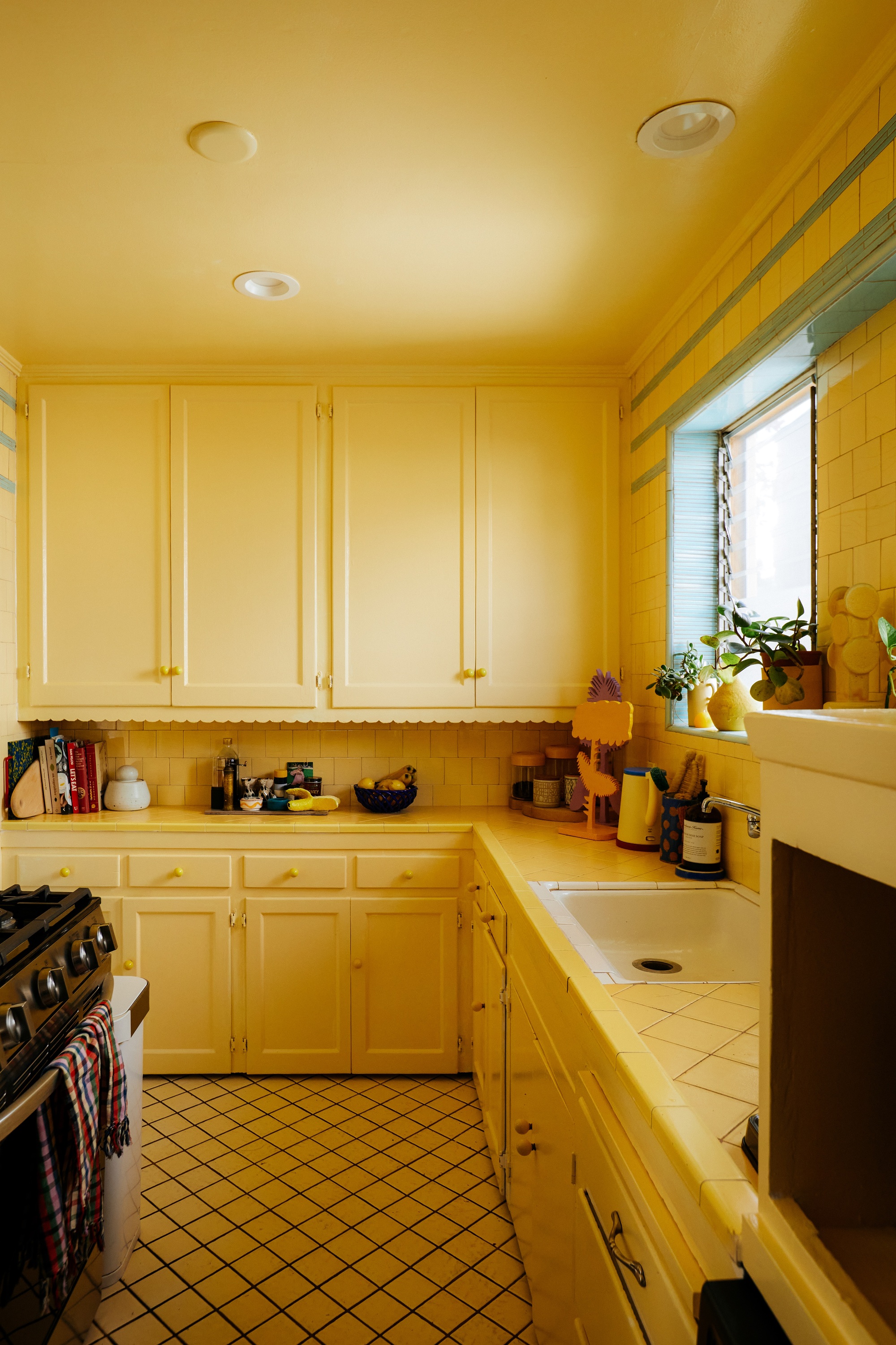 Image of a yellow, retro kitchen with yellow floor and backsplash tiles, yellow countertops, yellow scalloped cabinets, and yellow ceilings.