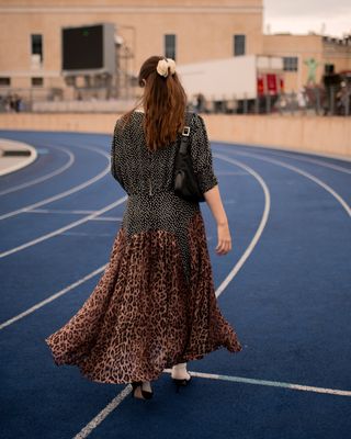 a fashion editor walks down a track during Copenhagen Fashion Week wearing a leopard print dress