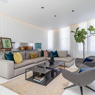 living room with white designed wall grey sofa with cushions and frames at wall