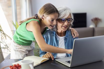 Shot of happy granmother using laptop with her granddaughter at home.