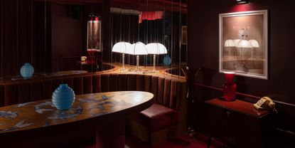 A dimly lit cocktail bar fuses 1970s European design with Japanese influences through plush leather and wood furniture, mirrored walls, and bespoke artworks.