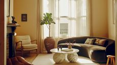 A renovated living room in a period London property with a curved sofa and blush pink walls