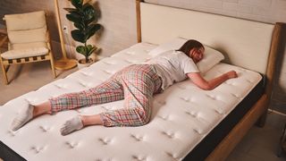 A person lies in a stomach sleeping position on the Firm side of the Plank Firm Mattress