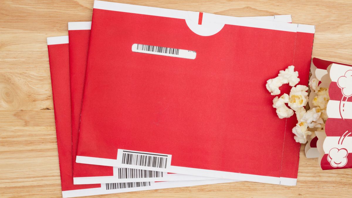 Netflix dvds on a table next to a bag of popcorn