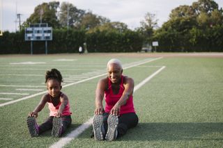 How long does it take to get fit: Grandmother and granddaughter stretching on football field
