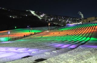 Snow tubing lanes are lit up at night at the Camelback Resort in the Poconos
