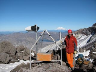 Installing an earthquake monitor at the summit of Mount St. Helens in Washington. Mount Rainier is in the background.