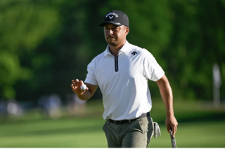 Xander Schauffele waves to the crowd after holing a putt