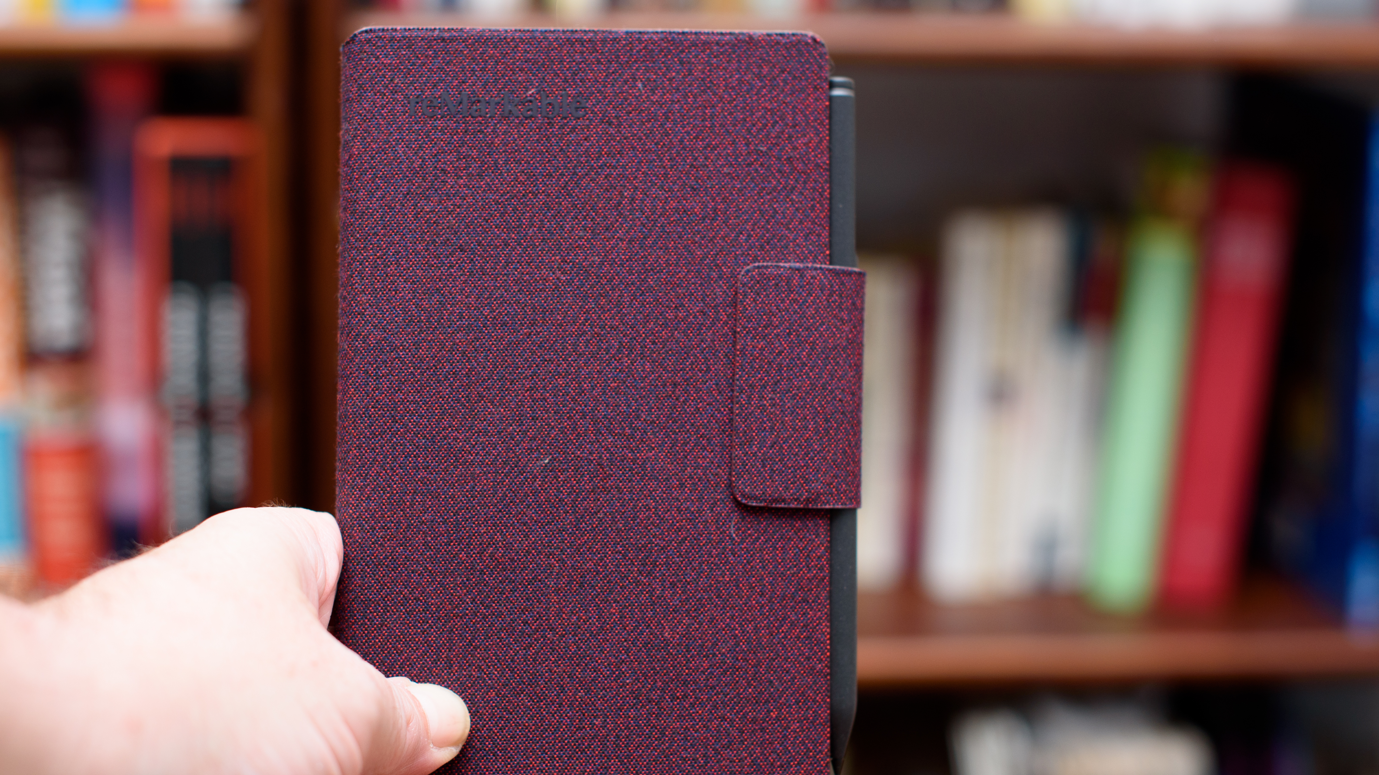 reMarkable Paper Pro Move tablet in front of a library of books, showing various writing screens and comparing the size to a Moleskine notebook
