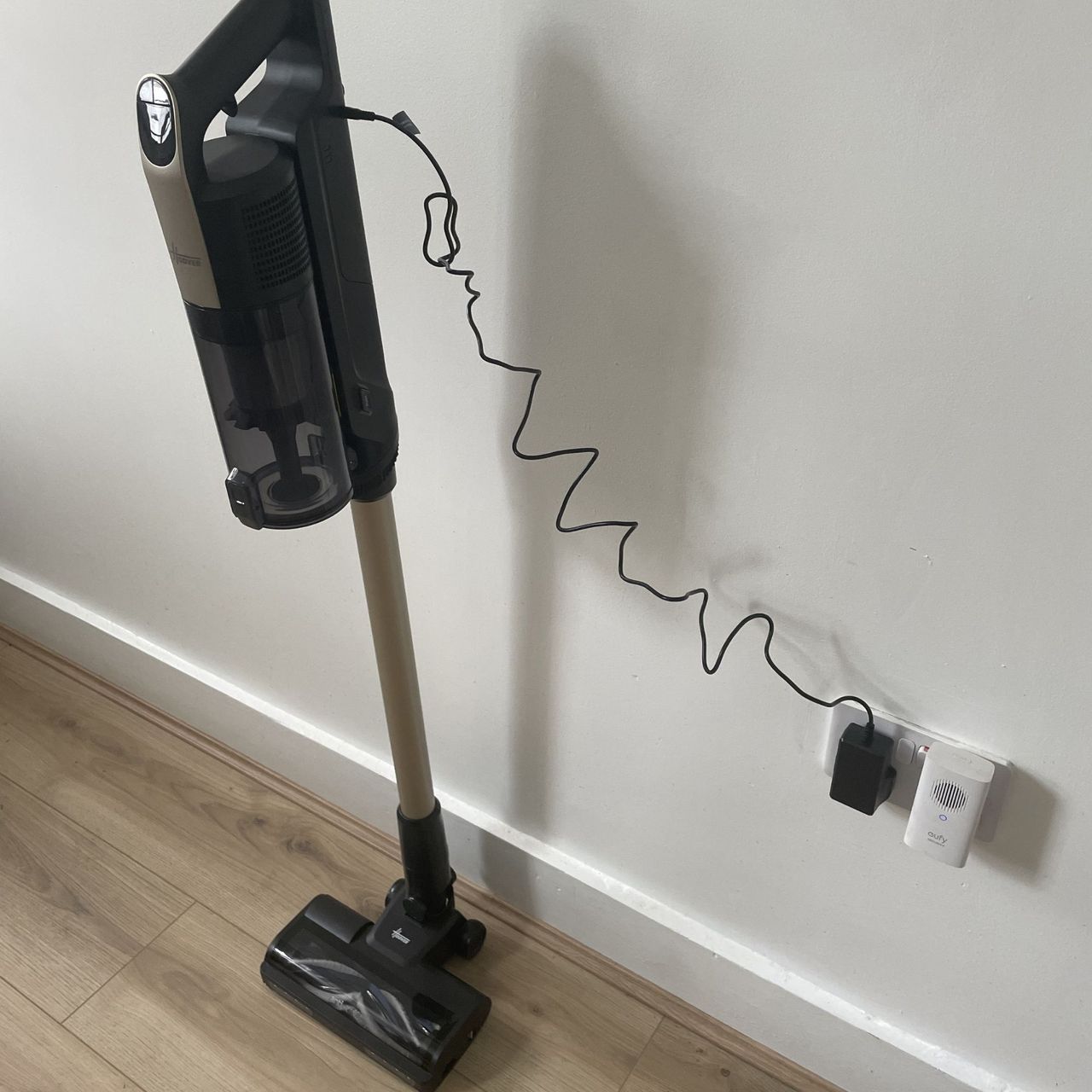 Hoover HF3 Pet DynamicClean Cordless Vacuum Cleaner sitting on wood-effect flooring, plugged in to the charger