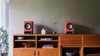 Technics SC-CX700 speakers in red finish on wooden console