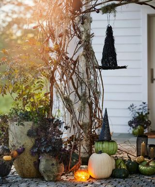 halloween porch decor with pumpkins foliage and a wicker witches hat