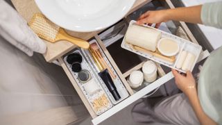 Someone organising a bathroom drawer with drawer inserts