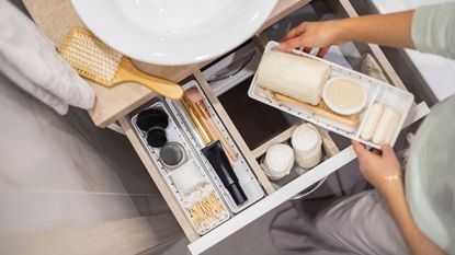 Someone organising a bathroom drawer with drawer inserts