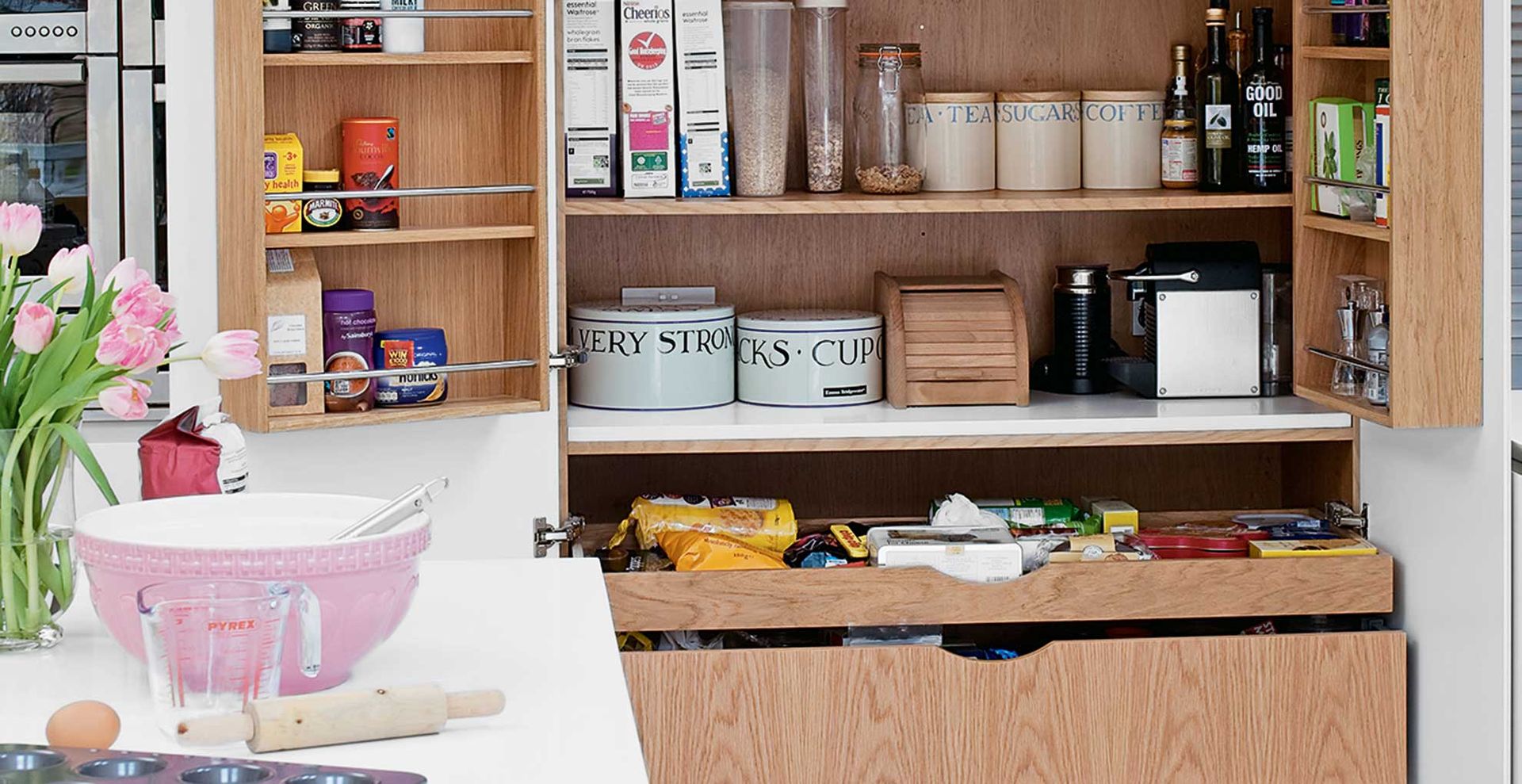 a cream kitchen with a pantry dresser shown with doors open with ingredients to show how to build a capsule kitchen