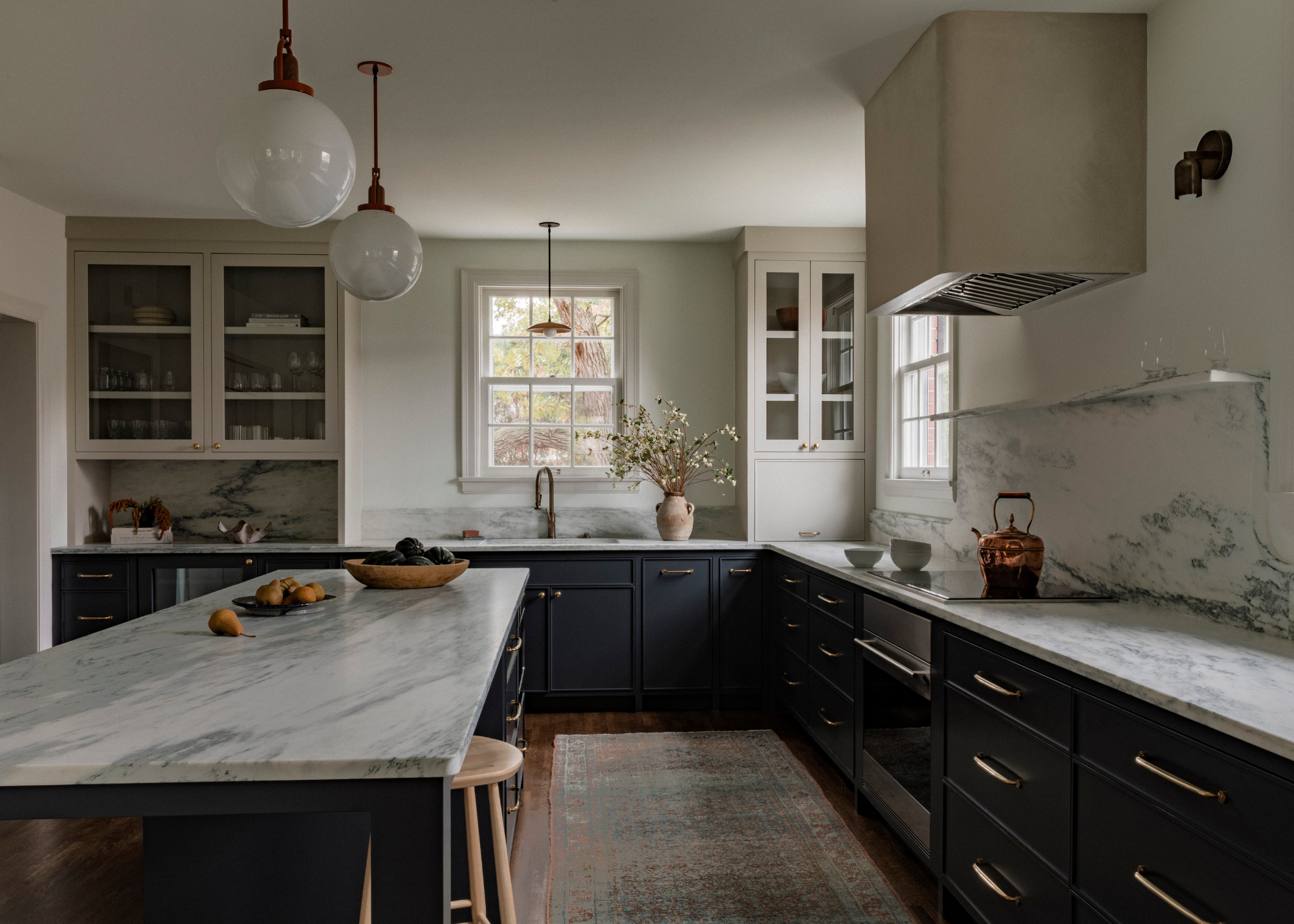 A calm muted navy blue kitchen with neutral walls and light worktops
