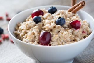 A bowl of oatmeal, with berries on top.
