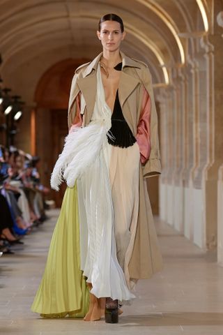 Woman on Victoria Beckham runway in pleated dress with feather and jacket