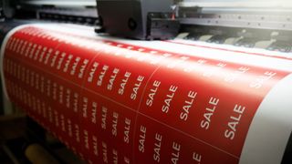 Printing a banner with the inscription 'sale' on the printing press. Large-format printing in production