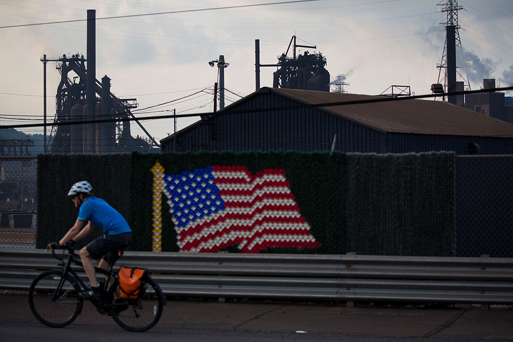 Man cycles past US flag