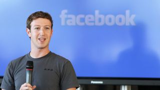Mark Zuckerberg standing in front of a Facebook banner