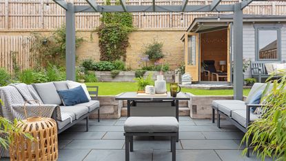 garden with summerhouse and lawn with a sunken paved area with outdoor furniture and pergola