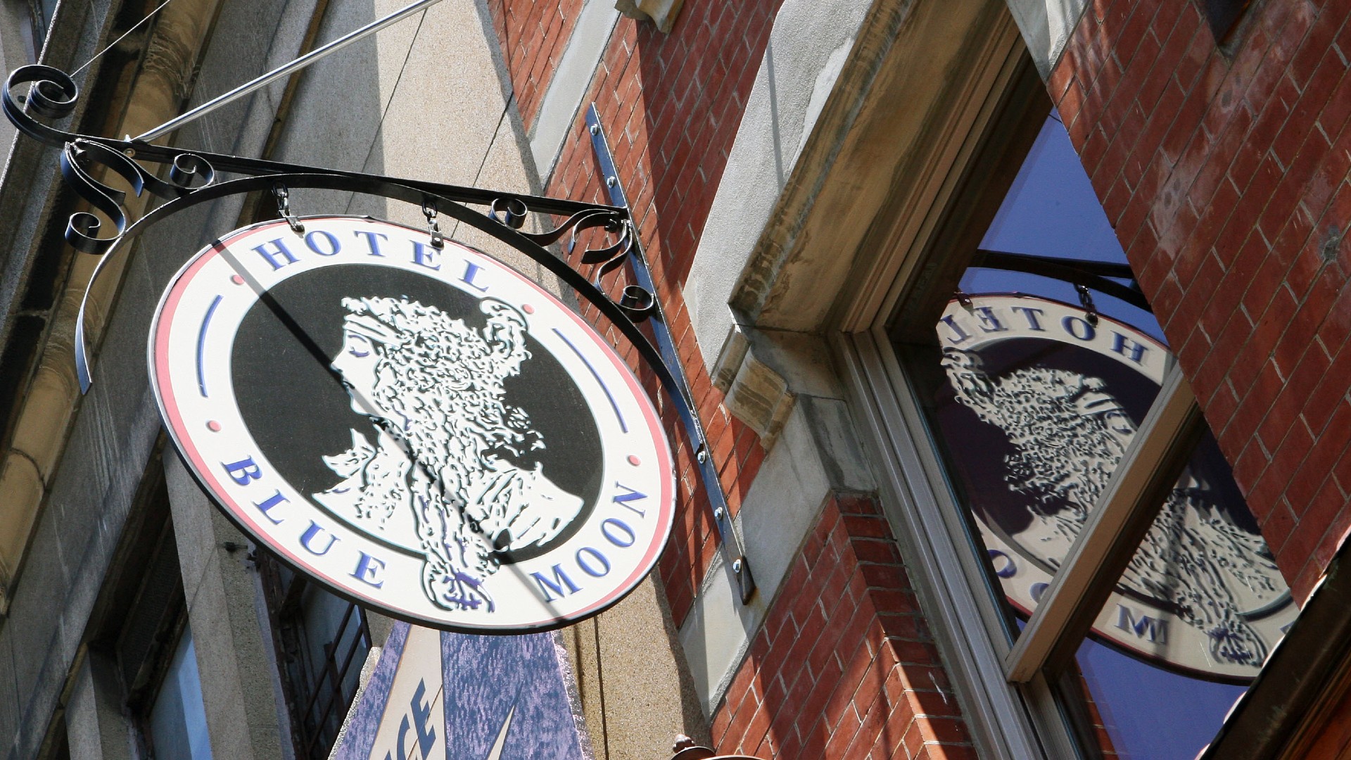a sign with the words "hotel blue moon" hangs from a brick wall