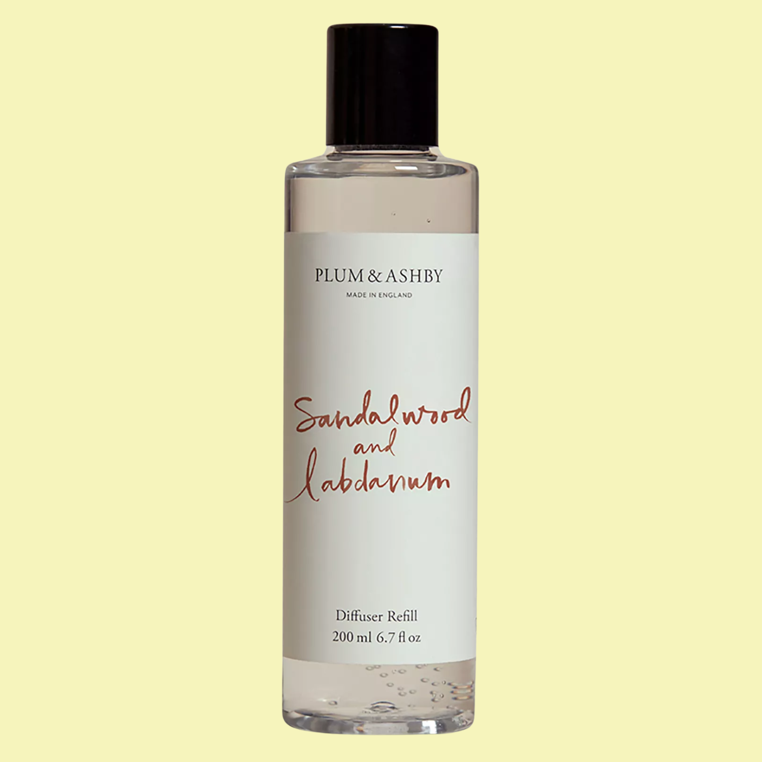 A bottle of reed diffuser refill against a butter yellow background