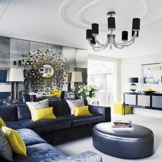 living room with velvet sofa and cushions with leather pouffe
