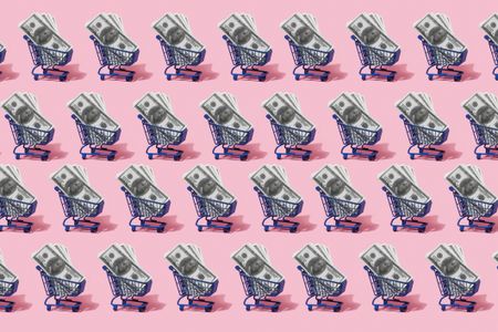 four rows of small blue shopping carts filled with hundred-dollar bills with a bright pink background