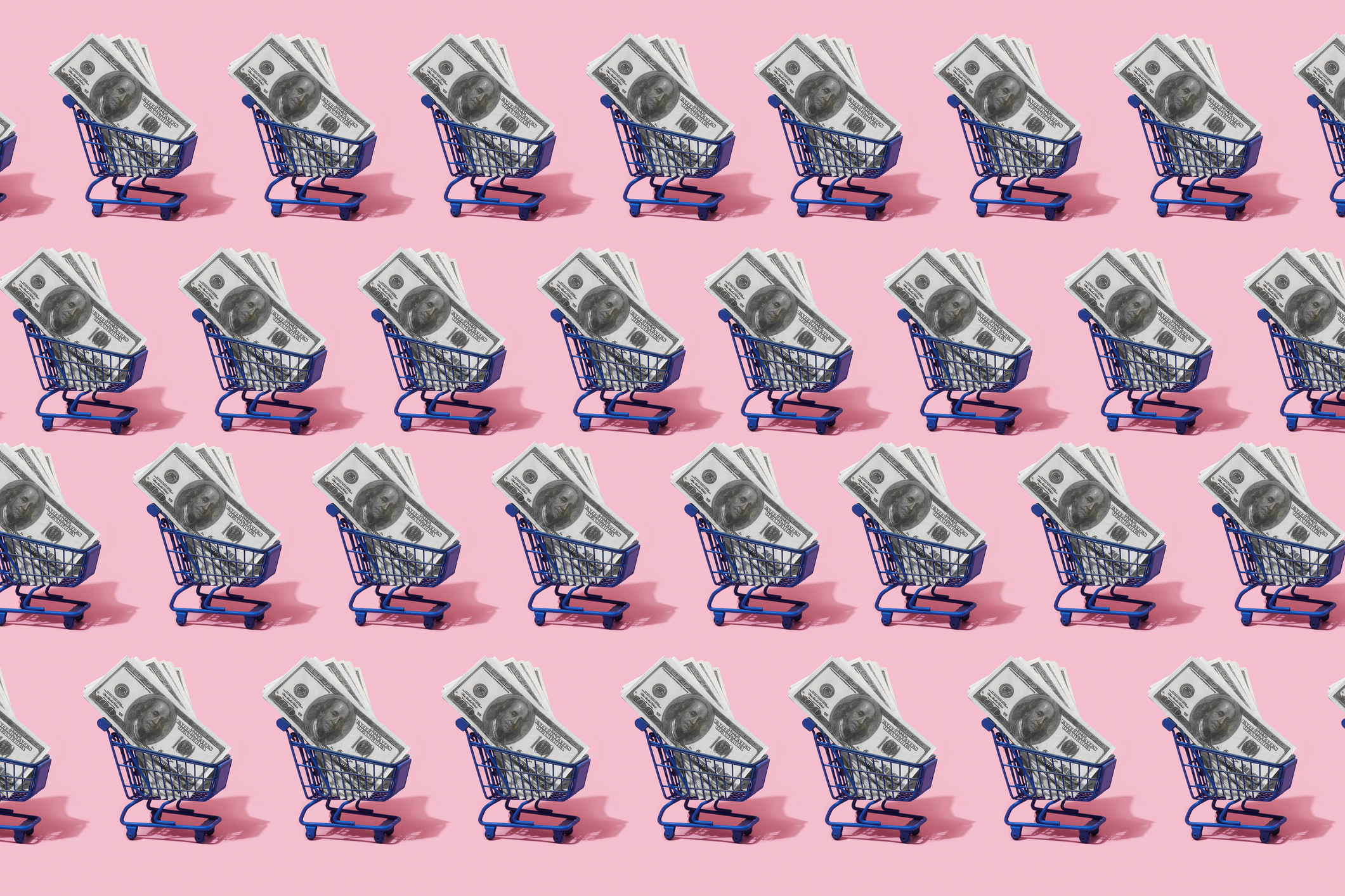 four rows of small blue shopping carts filled with hundred-dollar bills with a bright pink background