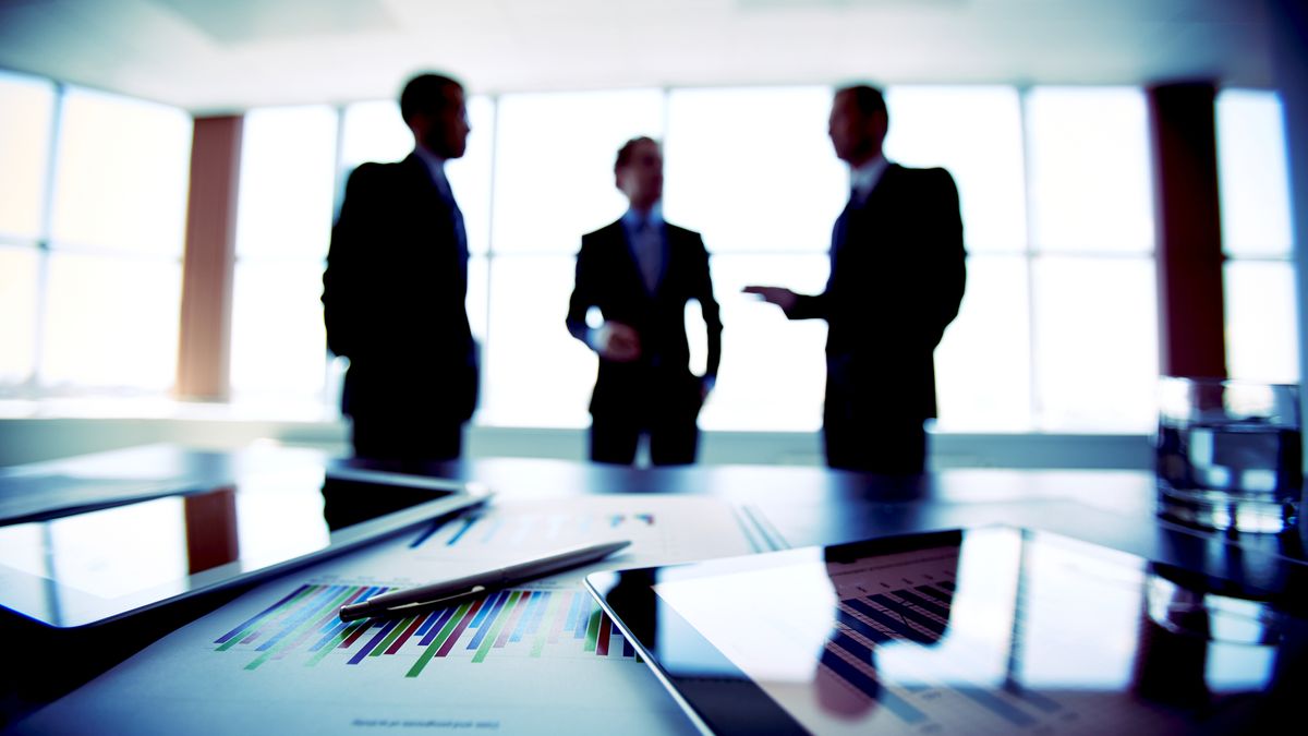 Boardroom with executives in suits standing and discussing a business decision