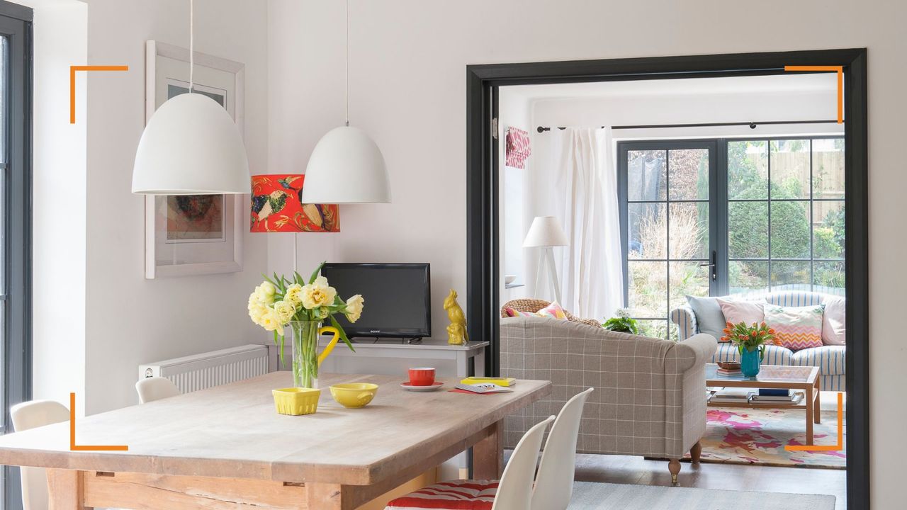 white open plan living space with dining table and lounge area beyond with large windows 