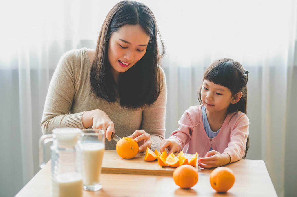 Woman and girl cut oranges