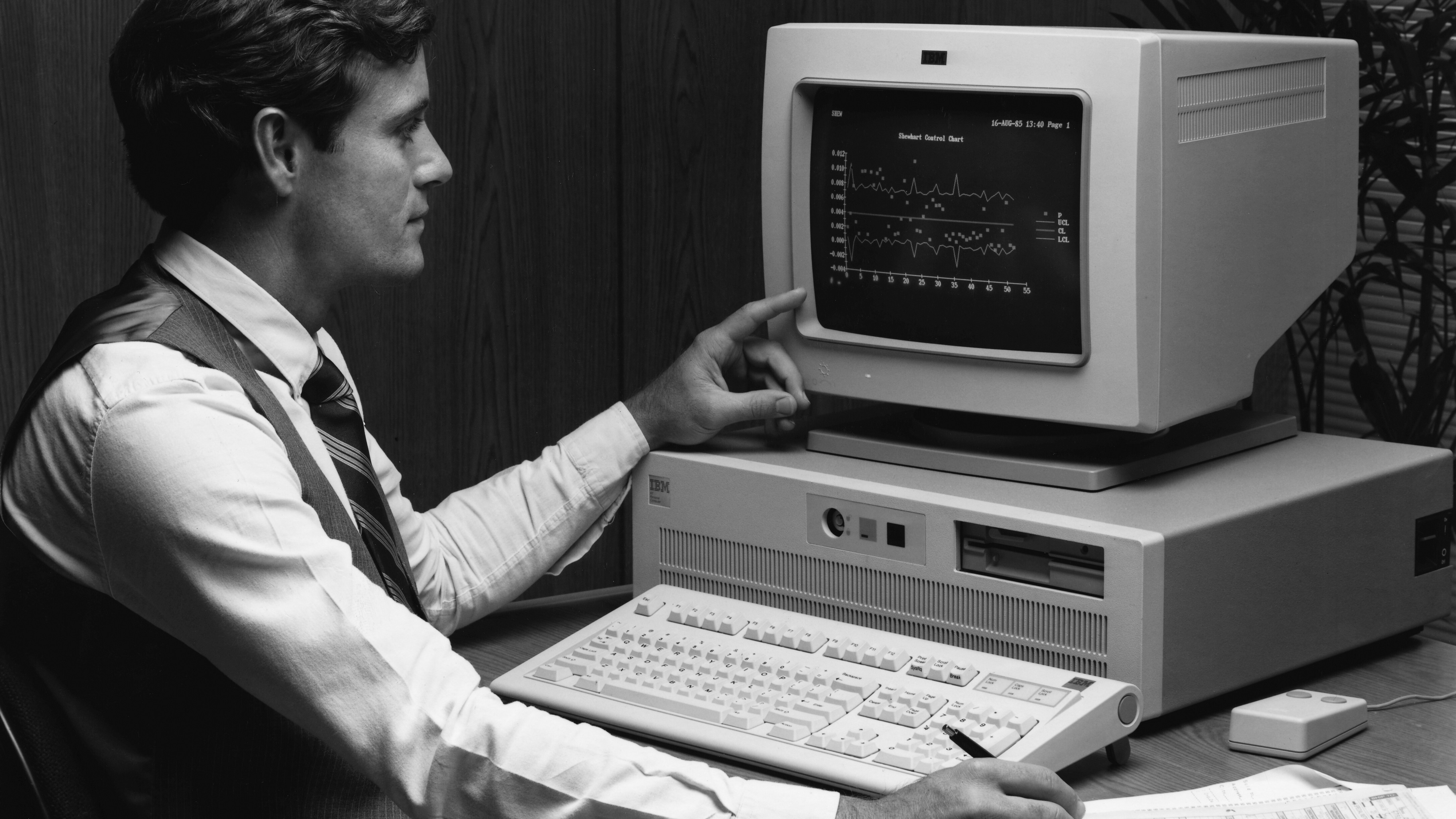 Guy pointing at his IBM PC in black-and-white, looking all busy and important