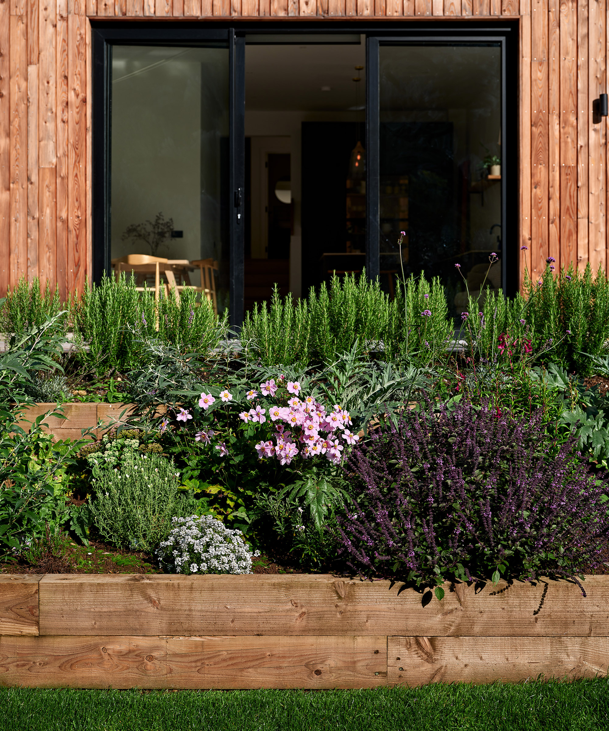 Tiered raised beds made with timber sleepers and planted with sun loving herbs and plants