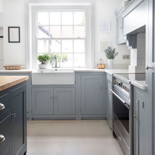 blue kitchen with large floor tiles and sink over belfast sink