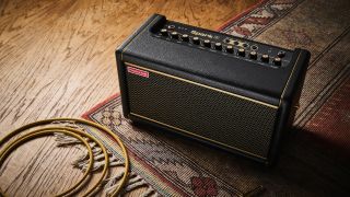 A Positive Grid Spark 2 guitar amp on a wooden floor with a rug and guitar cable