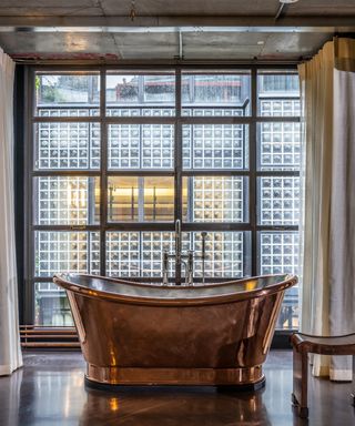 Tim Burton's house: Large brass freestanding tub in a luxe glass bedroom