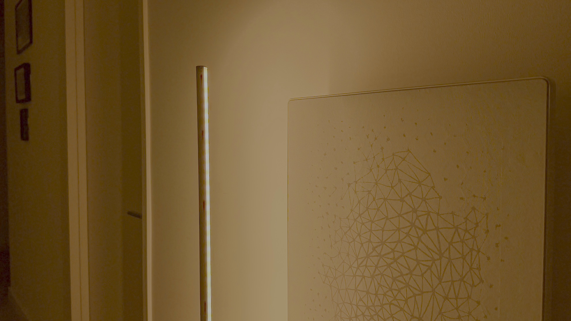 Nanoleaf Smart Multicolor Floor Lamp displaying a yellowish light beside a picture frame speaker