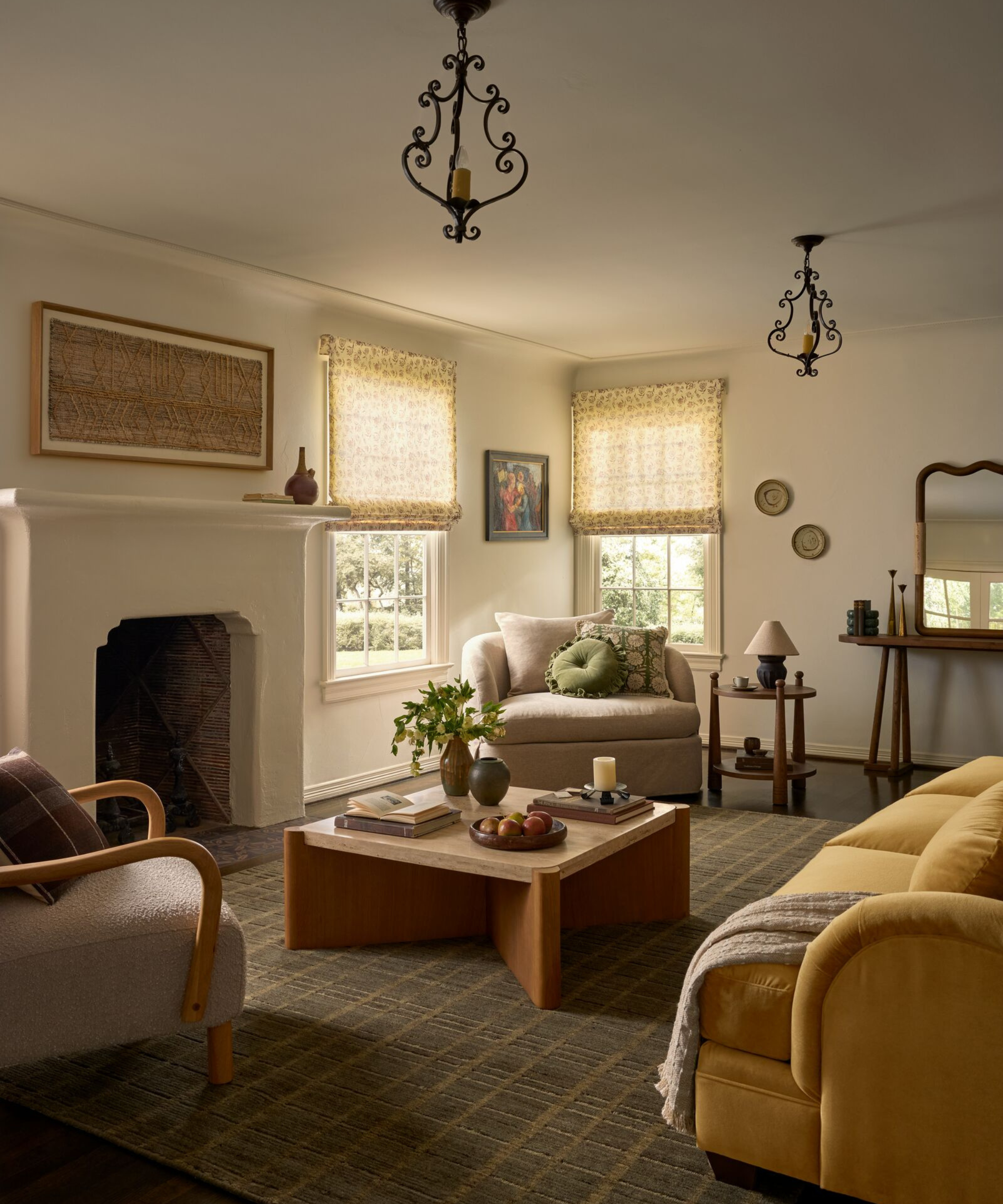 a cozy living room with a mustard yellow couch, a wooden coffee table, two accent chairs, and a large fireplace