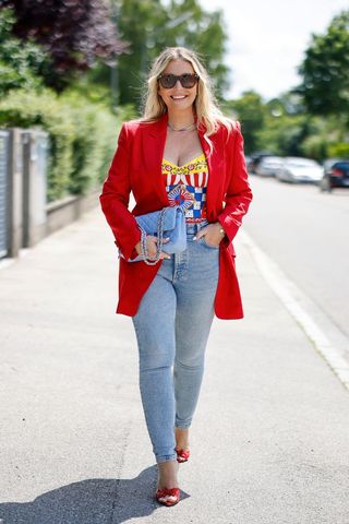 Woman wearing a red blazer and blue denim skinny jeans